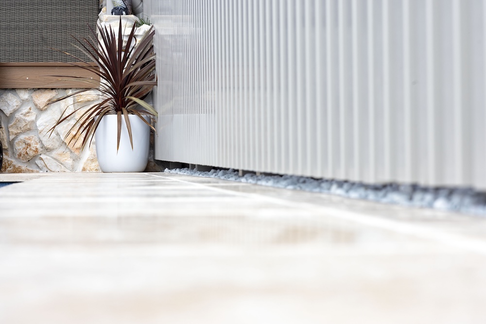 Pool surrounds landscaping in Cameron Park with pergola, decking, and travertine pavers. 