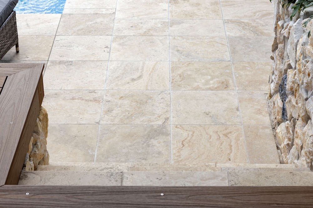 Pool surrounds landscaping in Cameron Park with pergola, decking, and travertine pavers. 