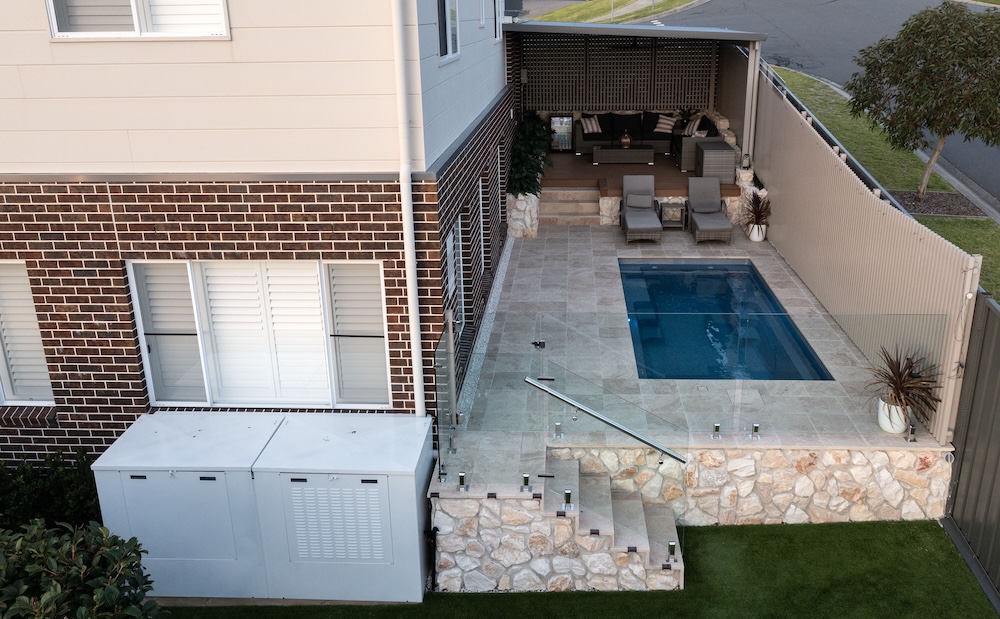Pool surrounds landscaping in Cameron Park with pergola, decking, and travertine pavers. 