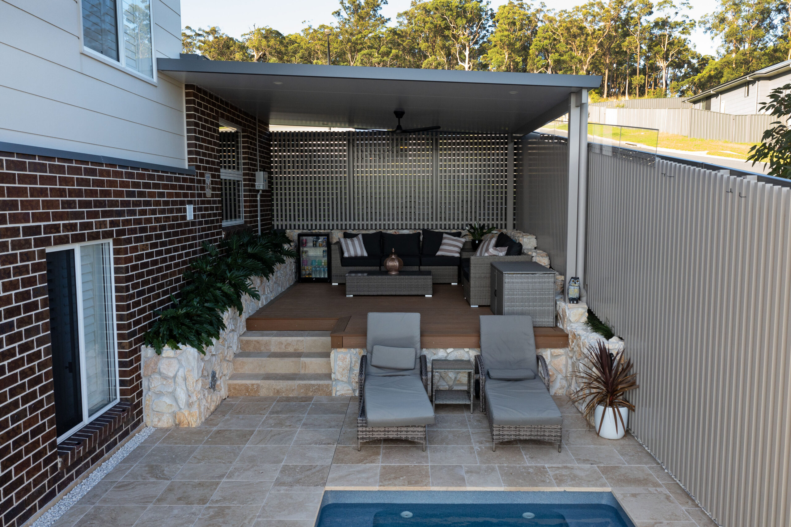 Pool surrounds landscaping in Cameron Park with pergola, decking, and travertine pavers.