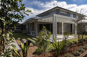 Domaine Display Homes in Thornton with completed landscaping, including a pergola, paving, turfing, firepit space, planting and gardens. 