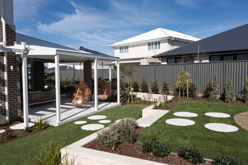 Commercial Domaine display home project in Cooranbong NSW consisting of decorative screening, turfing, retaining walls, steppers, fire pit space, concrete seating, planting and a pergola.