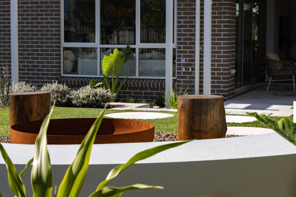 Commercial Domaine display home project in Cooranbong NSW consisting of decorative screening, turfing, retaining walls, steppers, fire pit space, concrete seating, planting and a pergola.