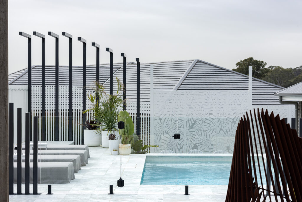 Completed pool surrounds landscaping project in Louth Park, including pool surround paving, decorative screening, glass pool fencing, and planting. 