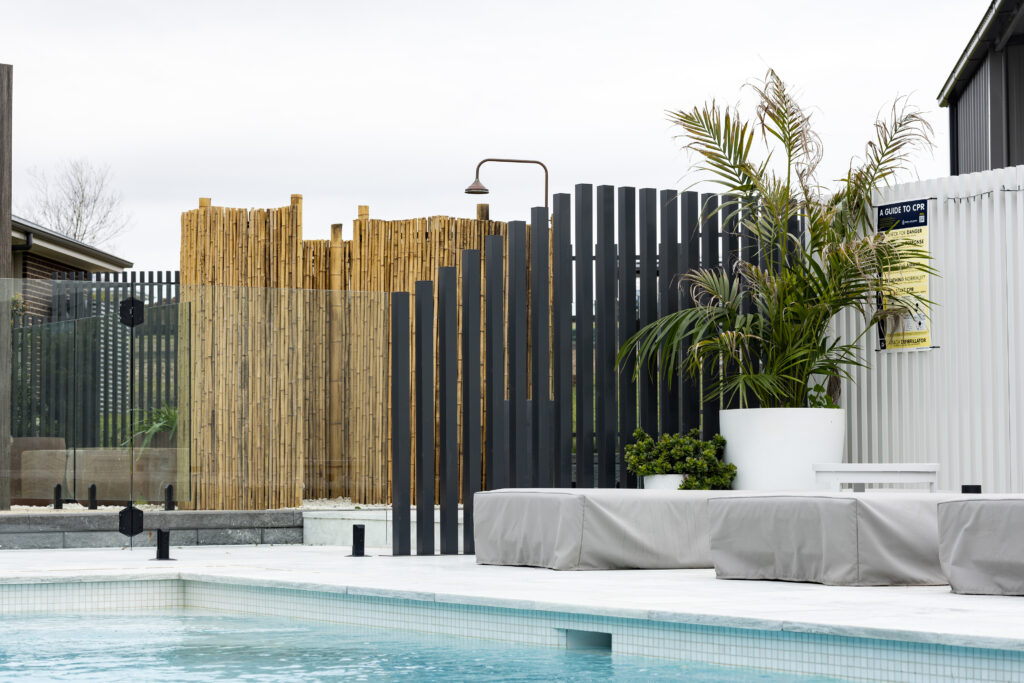 Completed pool surrounds landscaping project in Louth Park, including pool surround paving, decorative screening, glass pool fencing, and planting. 