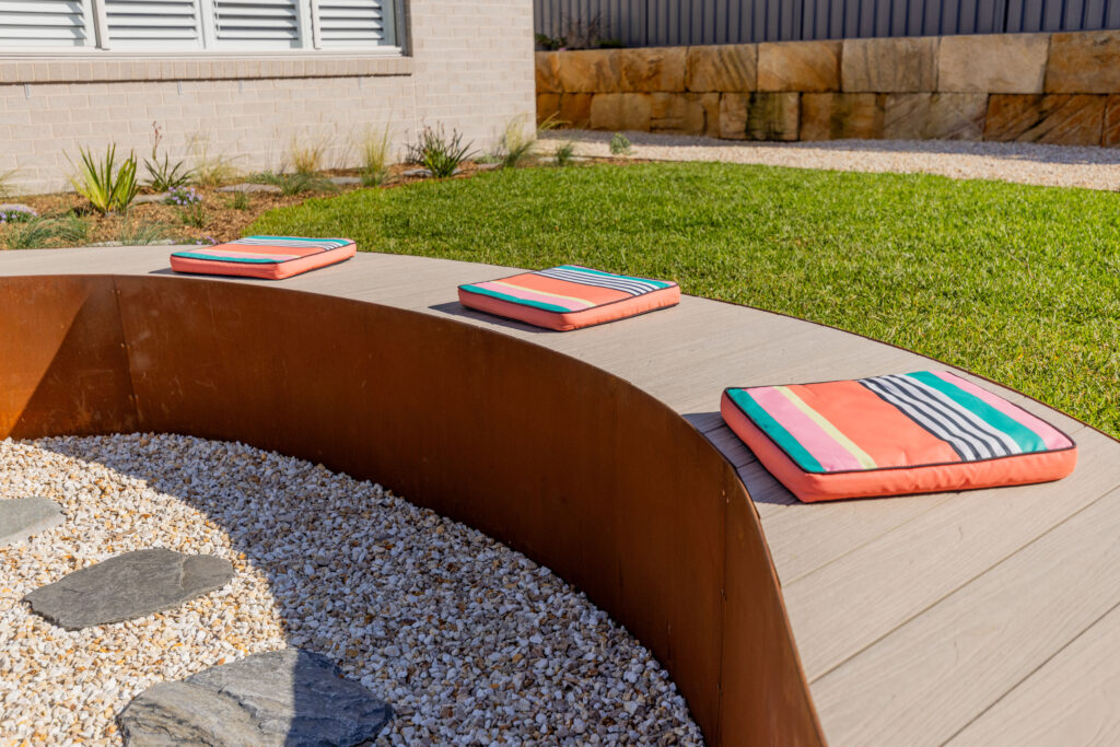 Curved corten steel garden seat with cushions, native garden design in Corlette