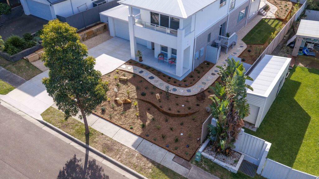 Aerial view of finished native garden design Corlette front yard with curved garden beds and stepping stone path