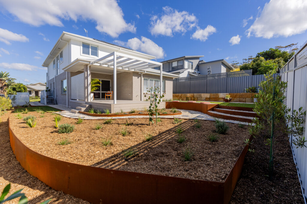 Native garden design Corlette rear yard with pergola, deck and sandstone retaining wall