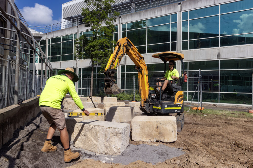 Excavator placing sandstone logs for the yarning circle at John Hunter Hospital