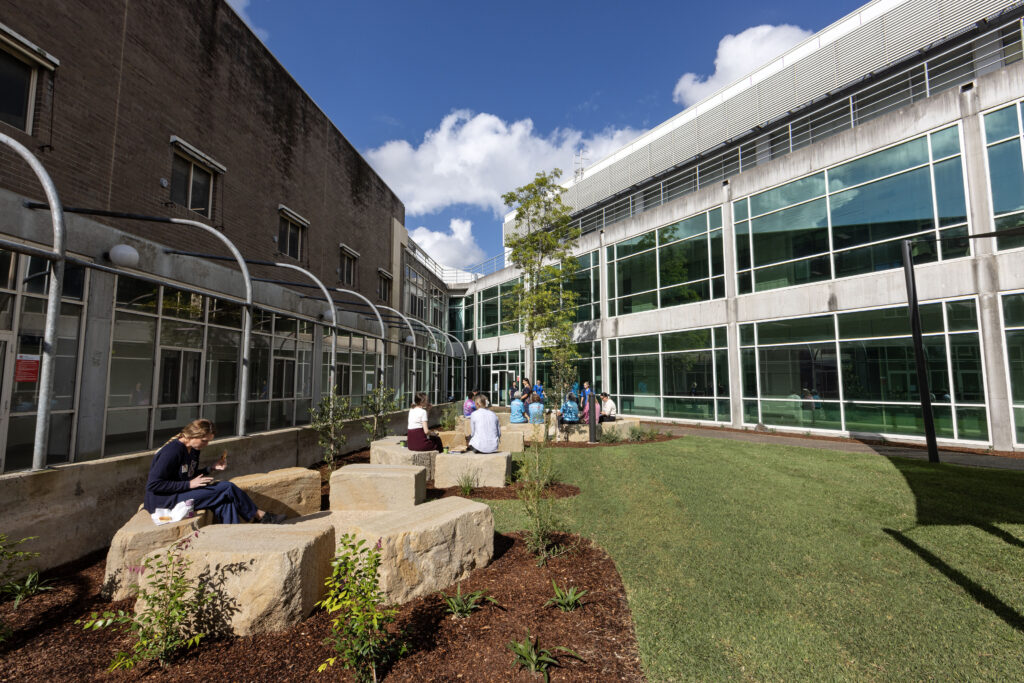 Hospital staff taking a lunch break on the sandstone seating at John Hunter Hospital