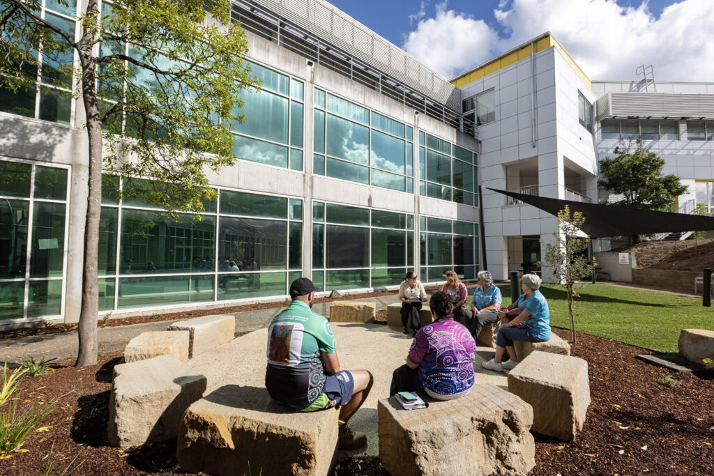 Group meeting in the yarning circle at John Hunter Hospital, with the hospital building behind