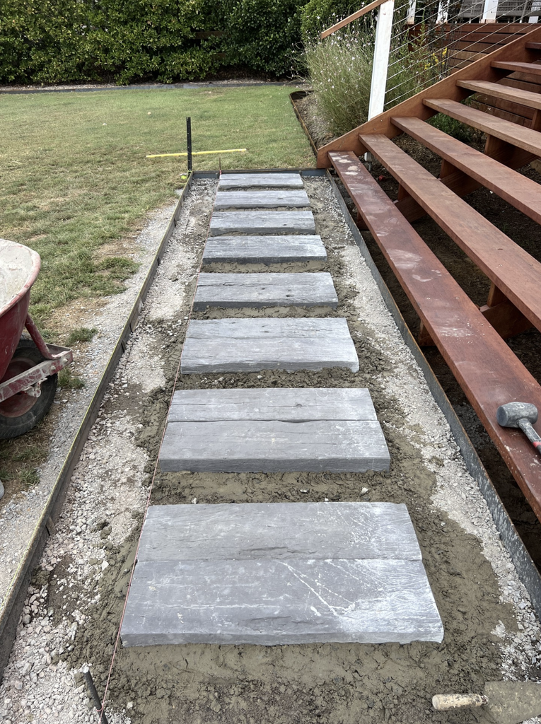 Concrete sleeper stepping stones being laid beside the deck stairs during pool landscaping in Pokolbin