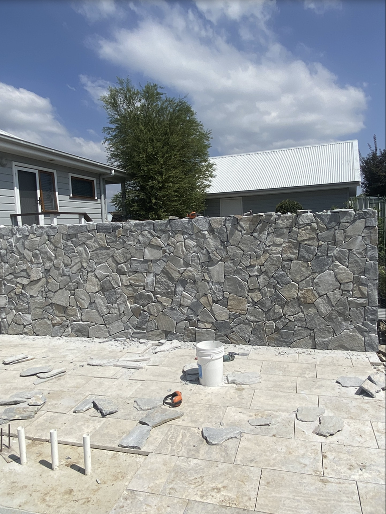Dry stack stone feature wall and silver travertine paving under construction for a Pokolbin pool landscaping project