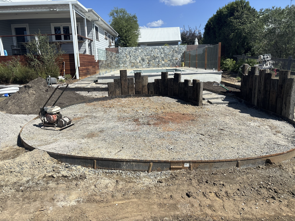 Circular firepit base with Corten steel edging and compacted gravel under construction in Pokolbin