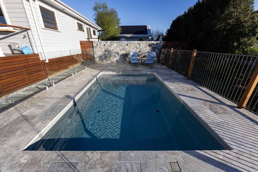 Wide view of the finished pool, stone feature wall and loungers in this Pokolbin backyard