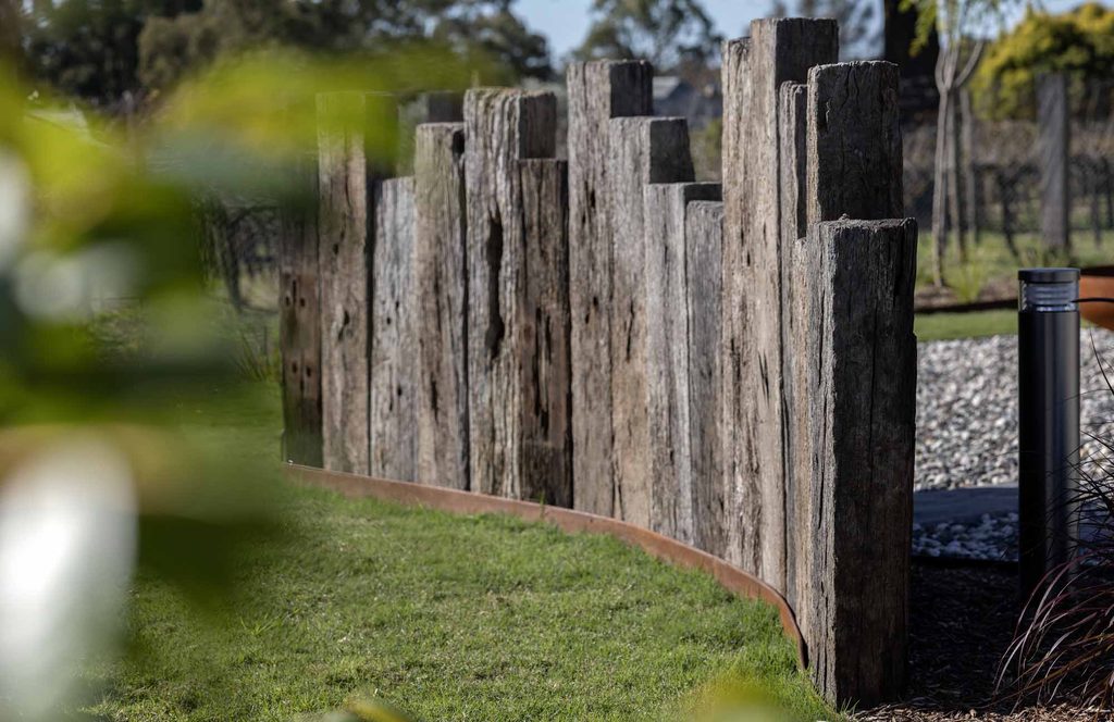 Close-up of recycled railway sleepers and Corten steel edging with vineyard trees in the background
