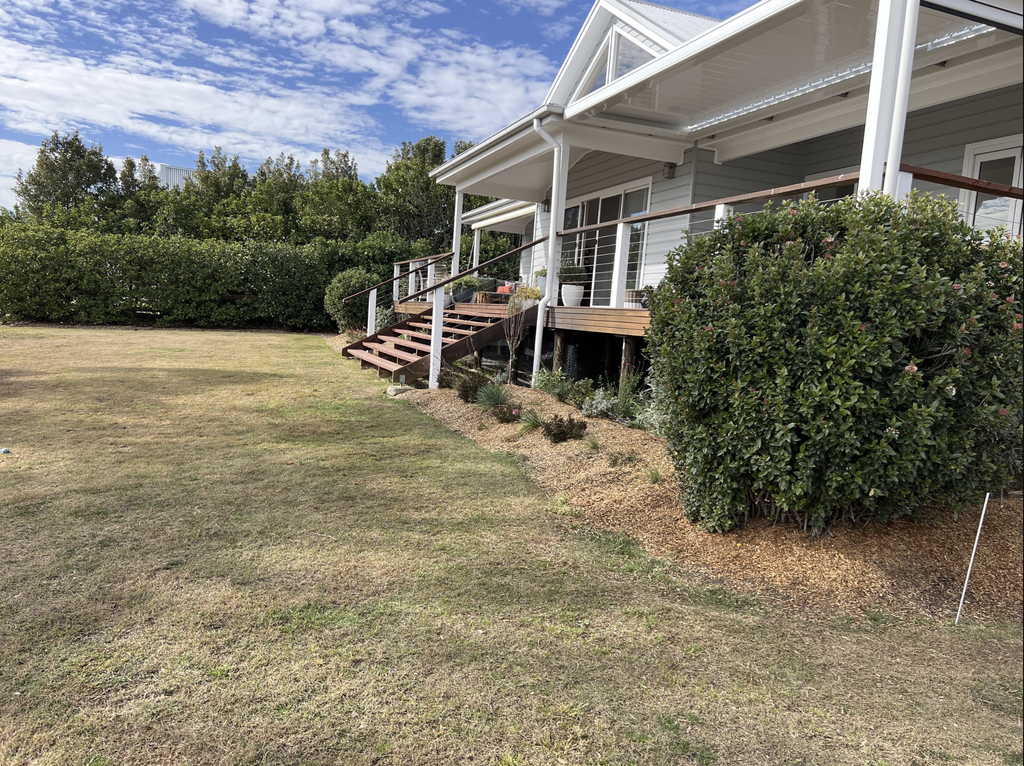 Side view of Pokolbin backyard before pool landscaping, showing deck, lawn and established hedge