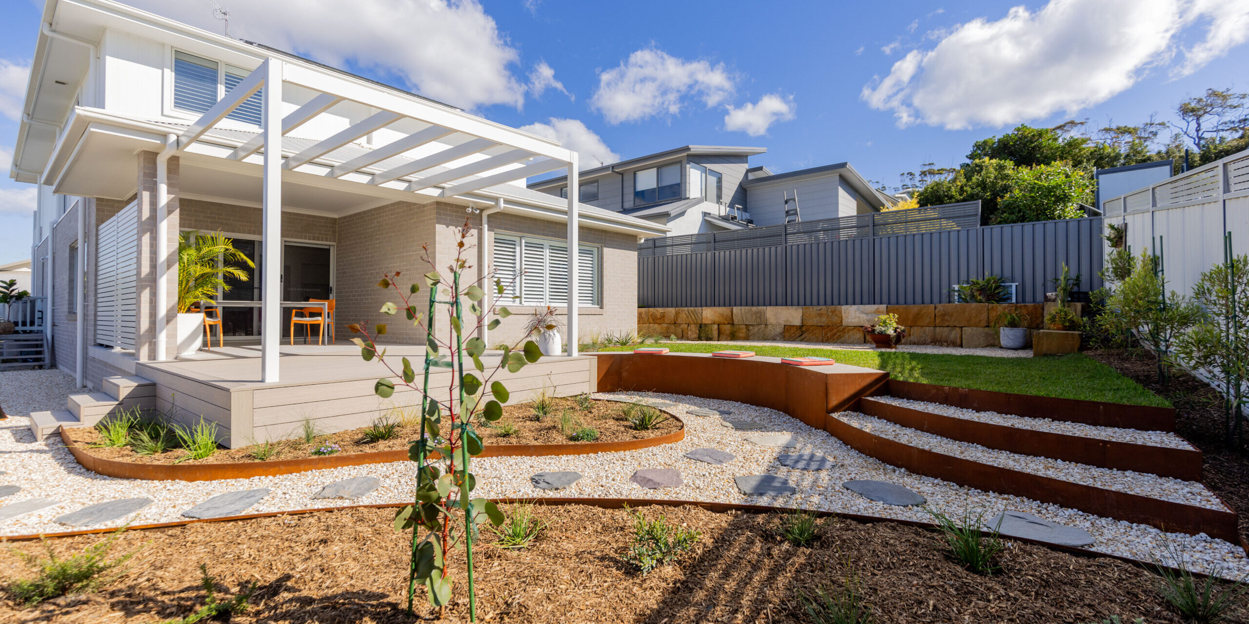 Native garden design Corlette rear yard with pergola, deck and sandstone retaining wall